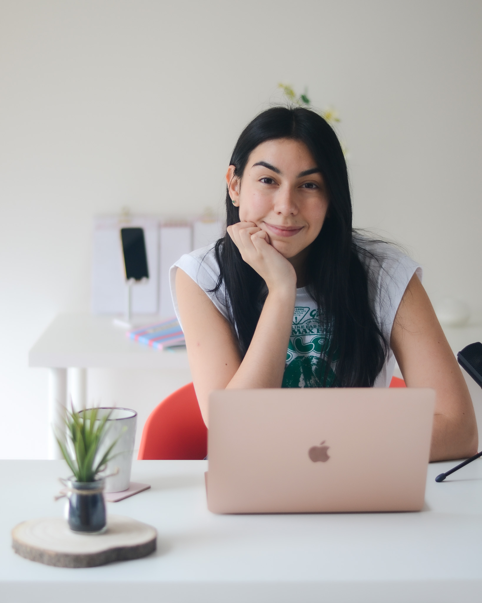Mayara Sousa at a white desk with her chin resting on her hand, an open laptop in front of her